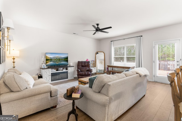 living room with a fireplace, light hardwood / wood-style flooring, and ceiling fan