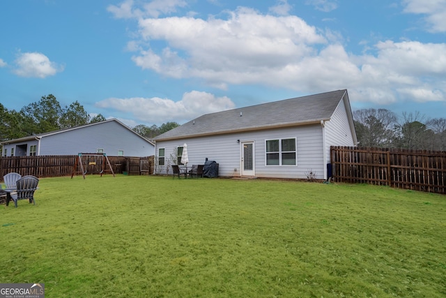 rear view of house featuring a playground and a lawn