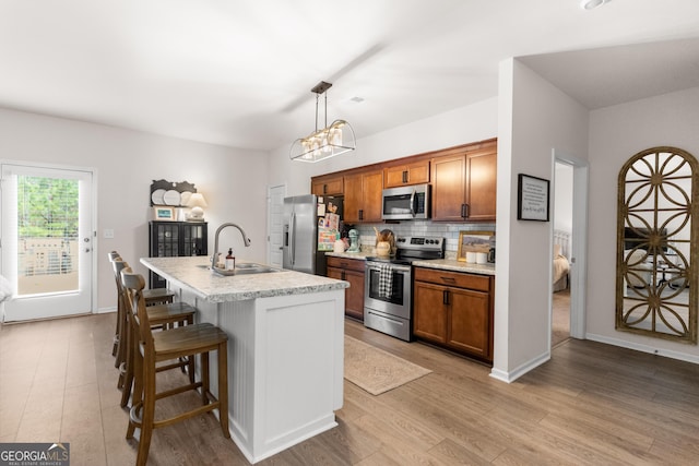 kitchen featuring sink, stainless steel appliances, an island with sink, pendant lighting, and a breakfast bar area