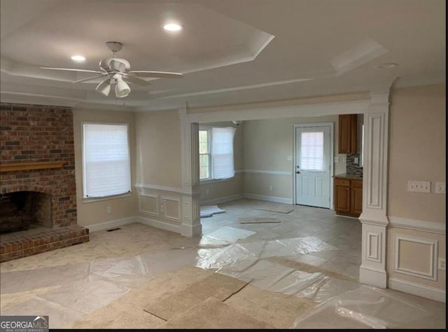 interior space featuring a tray ceiling, ceiling fan, and a fireplace