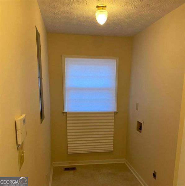 laundry room featuring a textured ceiling and hookup for a washing machine