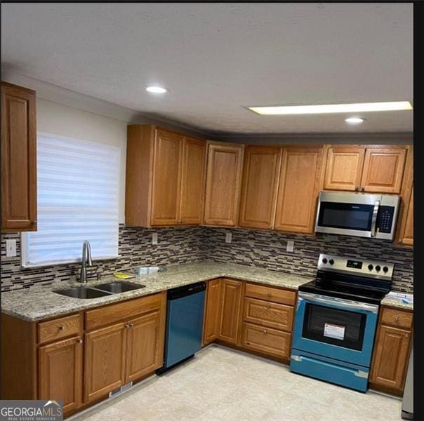 kitchen featuring appliances with stainless steel finishes, tasteful backsplash, light stone counters, and sink