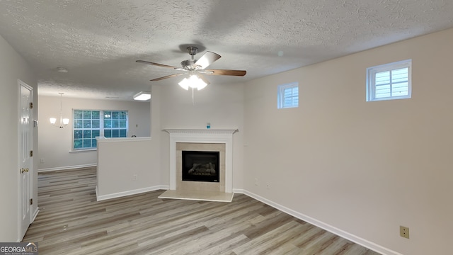 unfurnished living room with ceiling fan, a textured ceiling, and light wood-type flooring