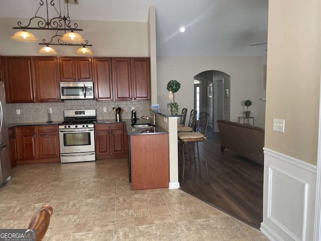 kitchen with a breakfast bar, sink, hanging light fixtures, kitchen peninsula, and stainless steel appliances