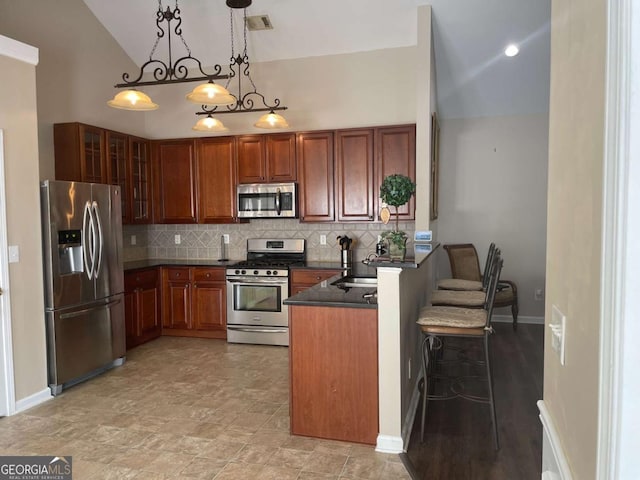 kitchen featuring decorative backsplash, a kitchen bar, kitchen peninsula, stainless steel appliances, and pendant lighting