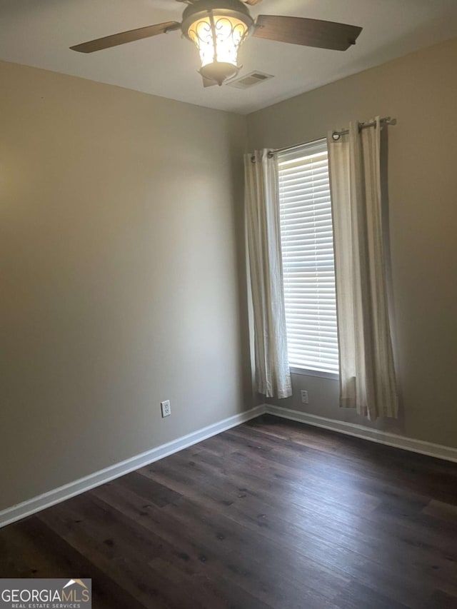 empty room with plenty of natural light, dark hardwood / wood-style floors, and ceiling fan