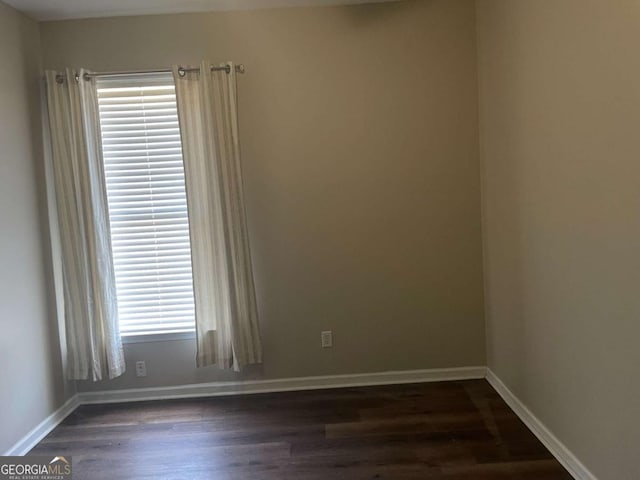 spare room with dark wood-type flooring and a healthy amount of sunlight