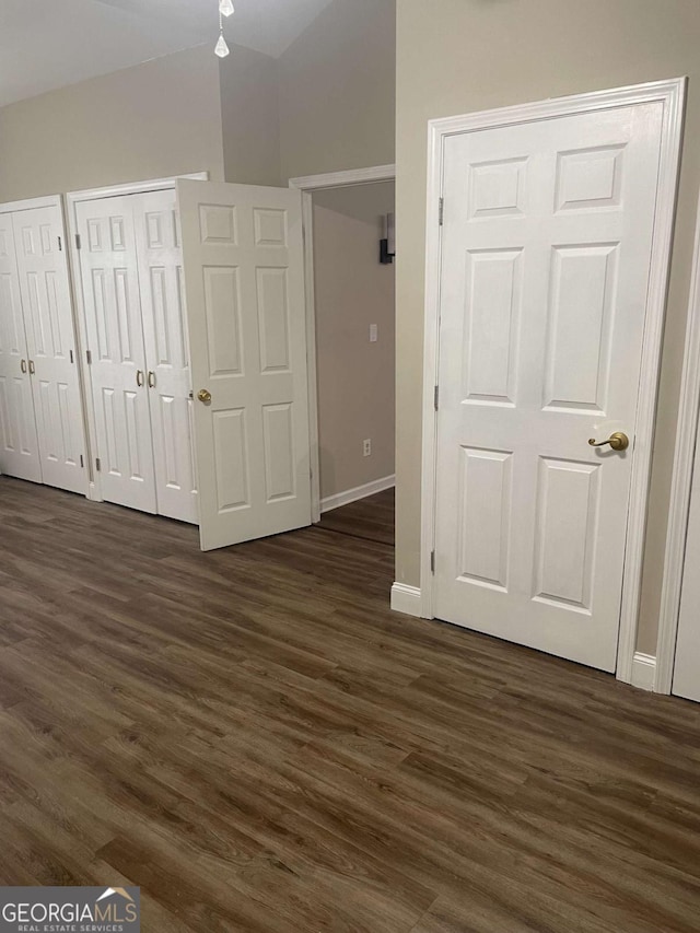 unfurnished bedroom with two closets and dark wood-type flooring