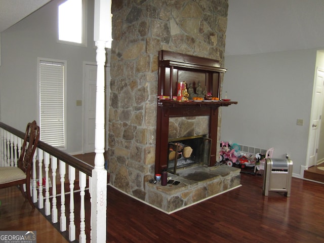 living room featuring a stone fireplace, wood-type flooring, and high vaulted ceiling