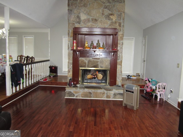 living room featuring vaulted ceiling, a stone fireplace, dark wood-type flooring, and crown molding