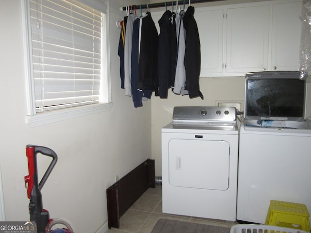 washroom with cabinets, light tile patterned floors, and washing machine and clothes dryer