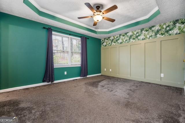 carpeted spare room featuring a tray ceiling, ceiling fan, crown molding, and a textured ceiling