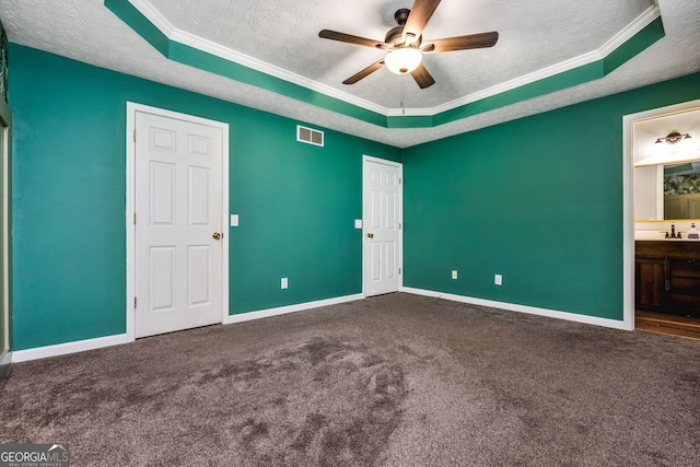 unfurnished bedroom featuring a raised ceiling, ensuite bath, and ceiling fan