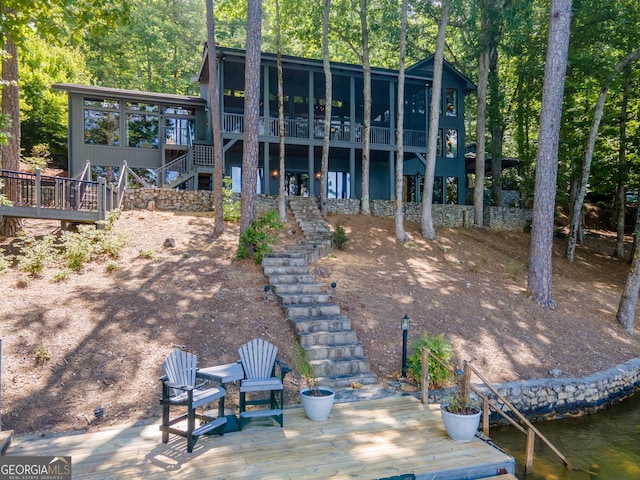 rear view of property featuring a sunroom and a deck with water view