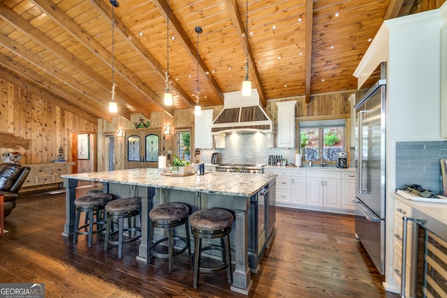 kitchen with beam ceiling, light stone counters, pendant lighting, white cabinets, and wood ceiling