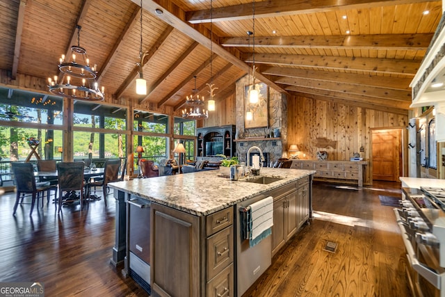 kitchen featuring sink, pendant lighting, beam ceiling, a fireplace, and an island with sink