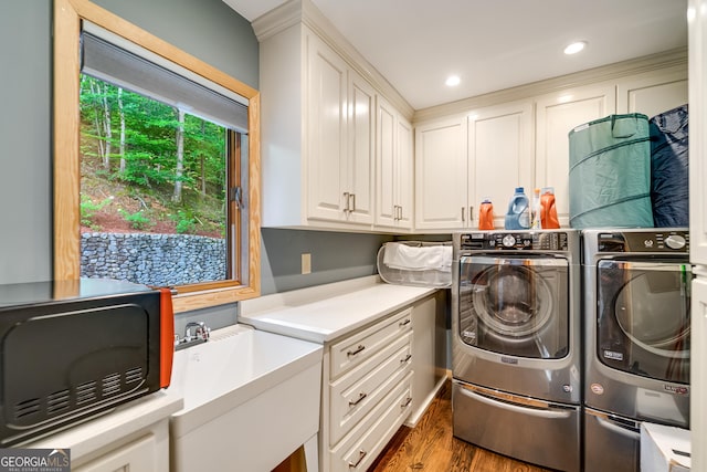 clothes washing area with washer and clothes dryer, dark hardwood / wood-style floors, cabinets, and sink