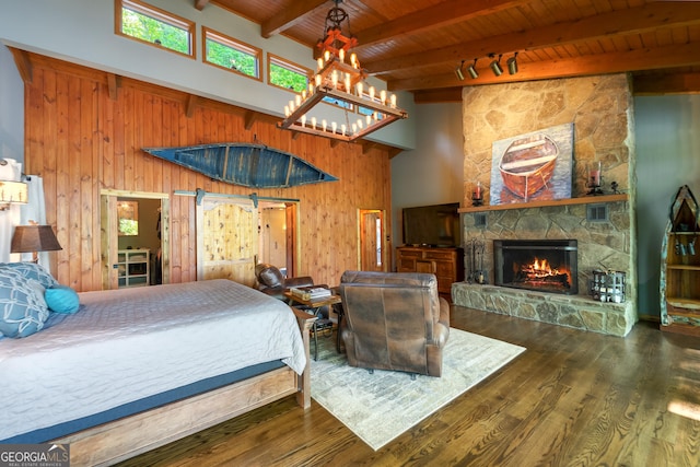 bedroom with dark hardwood / wood-style flooring, beamed ceiling, wood walls, a fireplace, and wood ceiling