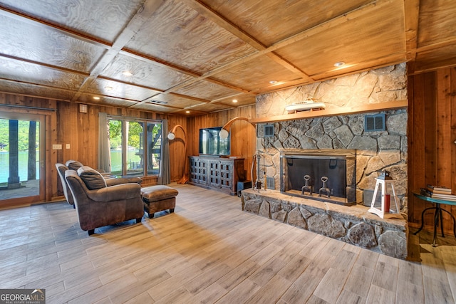 living room featuring a stone fireplace, wood ceiling, wooden walls, and coffered ceiling