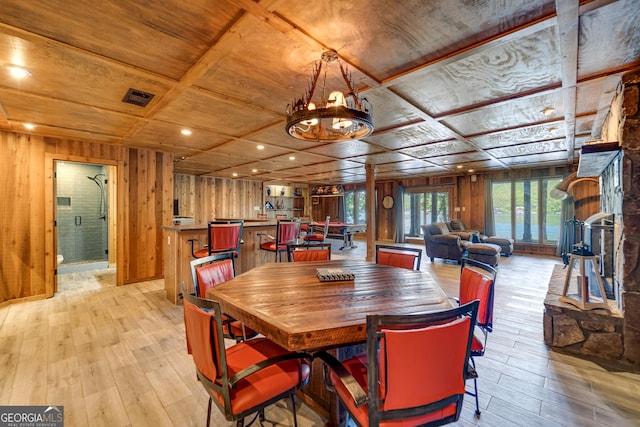 dining area featuring wooden ceiling, coffered ceiling, an inviting chandelier, wooden walls, and light wood-type flooring