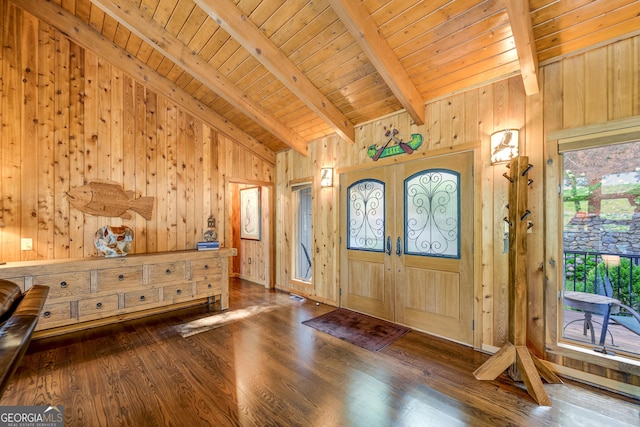 foyer with lofted ceiling with beams, wood walls, wooden ceiling, and french doors