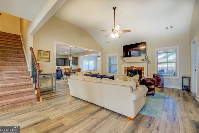 living room featuring a brick fireplace, vaulted ceiling, light hardwood / wood-style floors, and ceiling fan