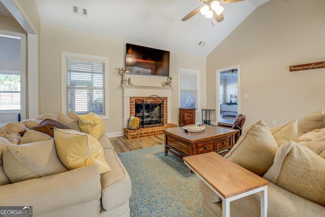 living room featuring ceiling fan, a fireplace, light hardwood / wood-style floors, and a wealth of natural light