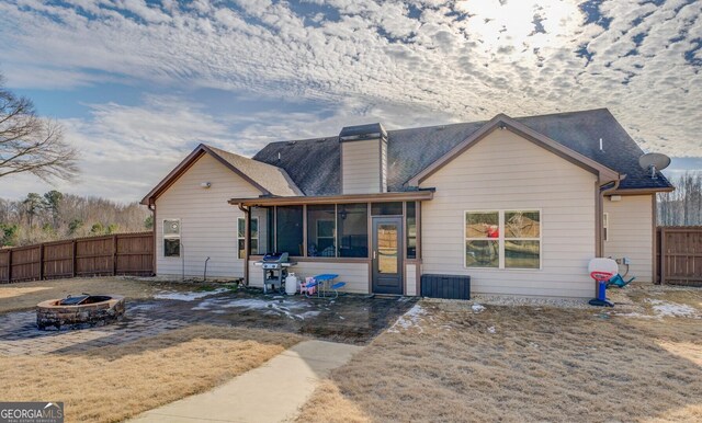 back of property featuring an outdoor fire pit and a sunroom