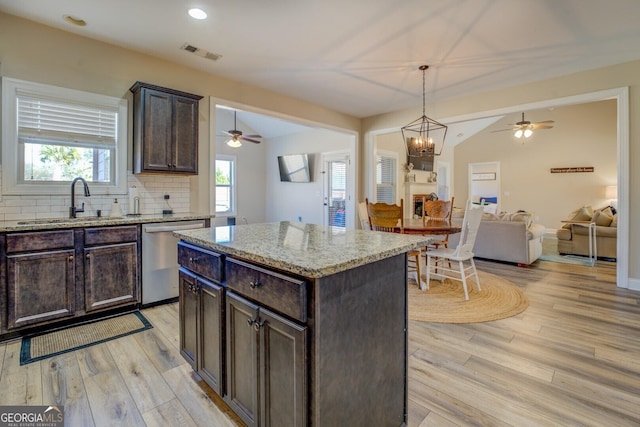 kitchen with sink, dark brown cabinets, a kitchen island, decorative backsplash, and stainless steel dishwasher