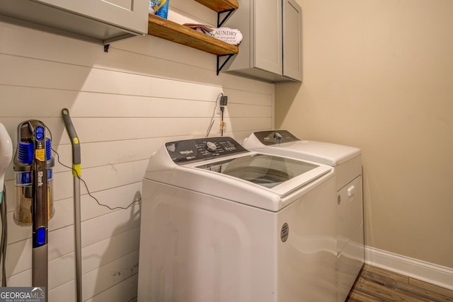 clothes washing area featuring cabinets, dark hardwood / wood-style floors, and washing machine and clothes dryer