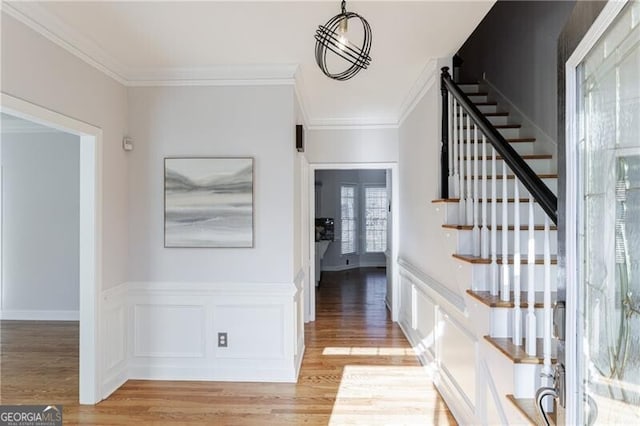 foyer entrance with ornamental molding and light wood-type flooring