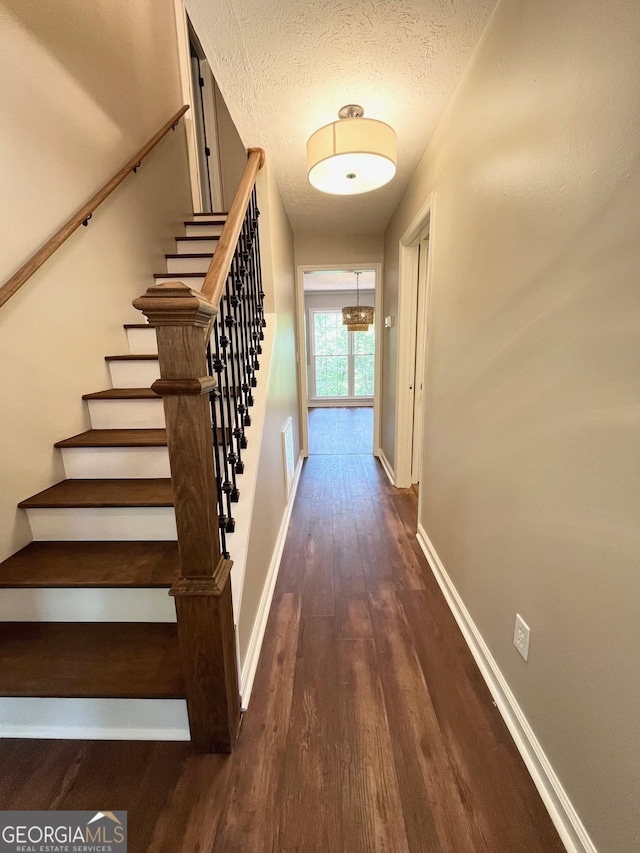 staircase with wood-type flooring and a textured ceiling