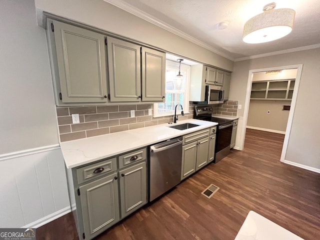 kitchen featuring sink, dark hardwood / wood-style floors, gray cabinets, ornamental molding, and appliances with stainless steel finishes