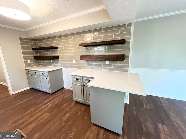 kitchen featuring gray cabinetry, a kitchen breakfast bar, a textured ceiling, dark hardwood / wood-style flooring, and kitchen peninsula