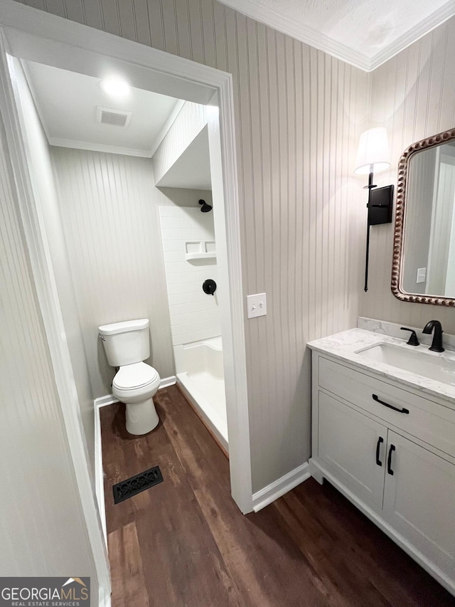 bathroom with crown molding, a shower, toilet, vanity, and hardwood / wood-style flooring