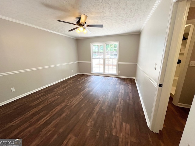 empty room featuring ceiling fan, dark hardwood / wood-style floors, crown molding, and a textured ceiling