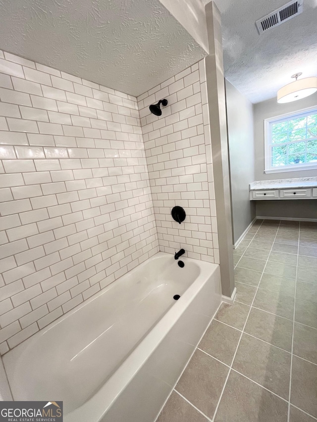 bathroom featuring a textured ceiling, tiled shower / bath combo, and tile patterned floors