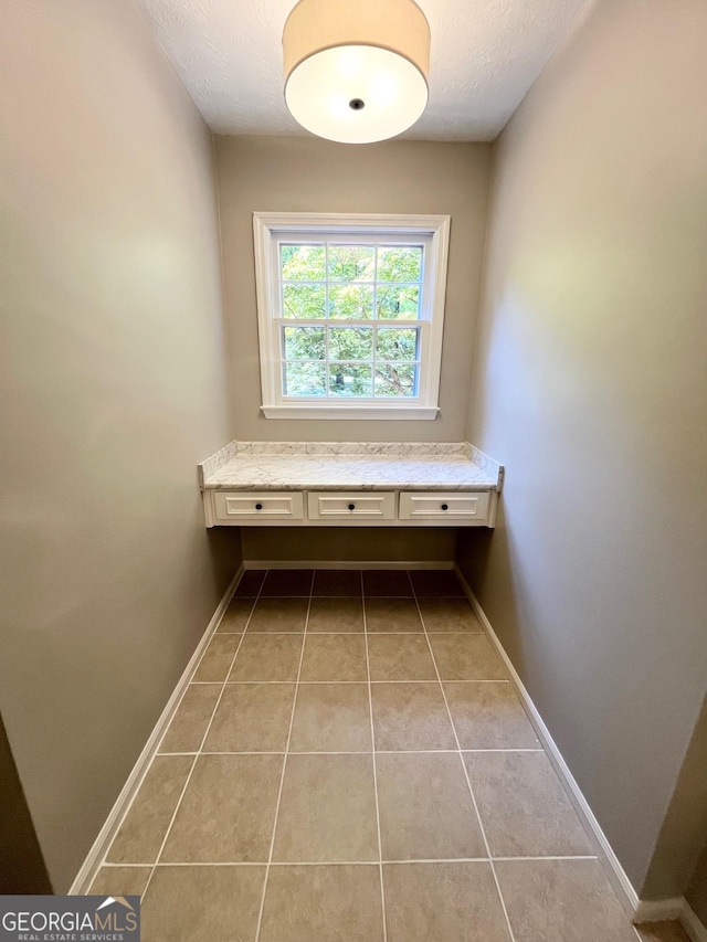 interior space with a textured ceiling and light tile patterned flooring