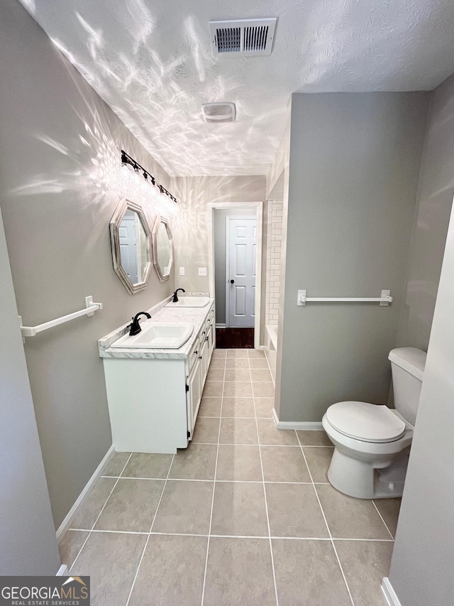 bathroom featuring tile patterned flooring, vanity, a textured ceiling, and toilet