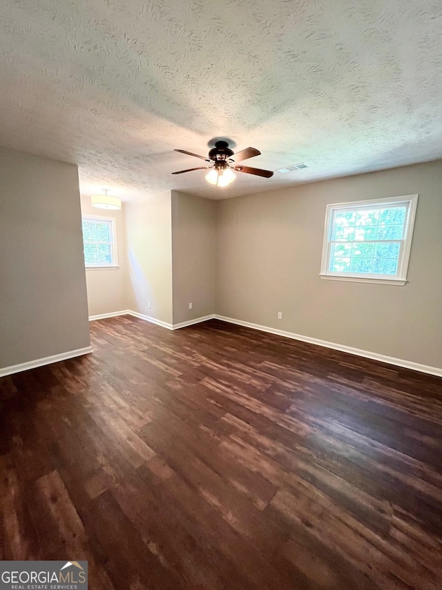 empty room with ceiling fan, dark hardwood / wood-style flooring, and a textured ceiling