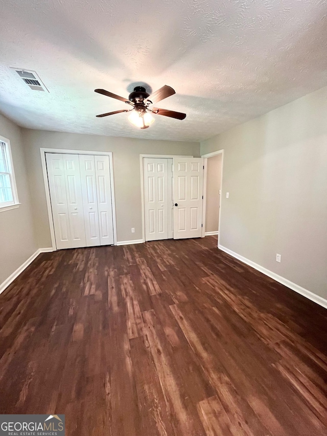 unfurnished bedroom featuring a textured ceiling, dark hardwood / wood-style floors, and ceiling fan