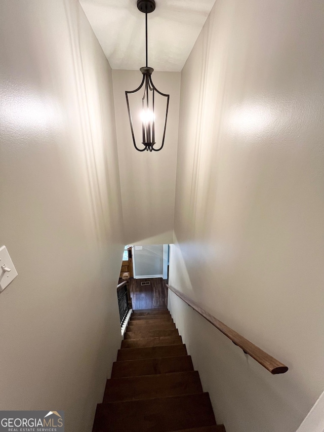 stairway featuring hardwood / wood-style floors and a chandelier