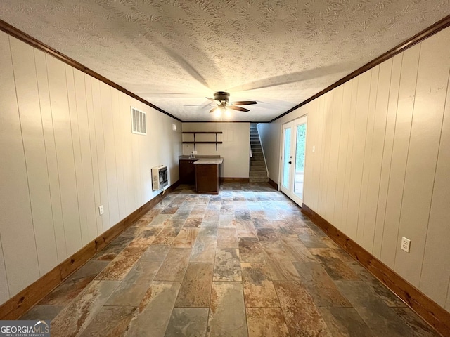 unfurnished living room with wooden walls, ceiling fan, and crown molding