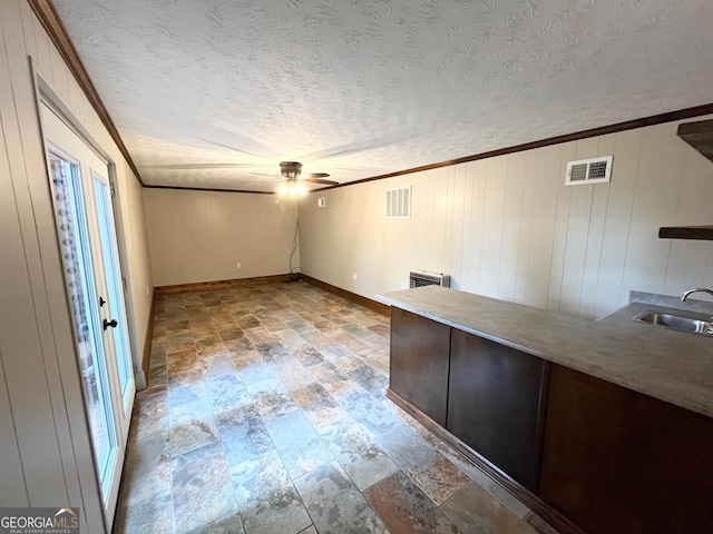 unfurnished office with sink, ceiling fan, crown molding, and wood walls