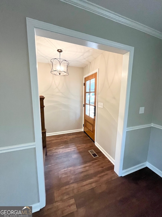 doorway with dark hardwood / wood-style flooring and crown molding