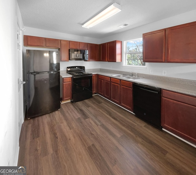 kitchen featuring black appliances, dark hardwood / wood-style flooring, sink, and a textured ceiling