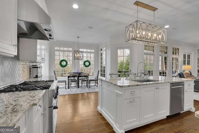 kitchen with white cabinets, an island with sink, hanging light fixtures, and sink