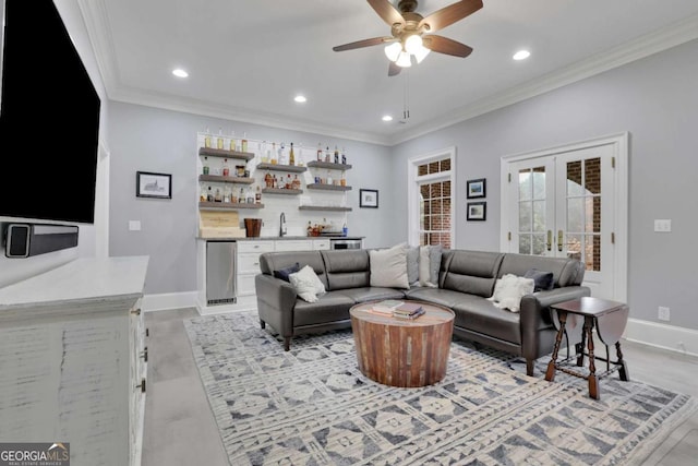 living room with ceiling fan, french doors, ornamental molding, and wet bar