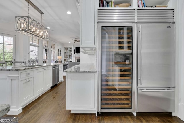 kitchen with white cabinets, sink, light stone countertops, appliances with stainless steel finishes, and decorative light fixtures