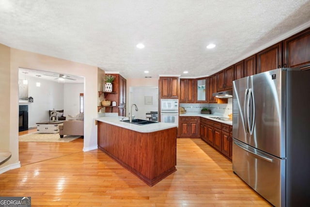 kitchen featuring stainless steel refrigerator, sink, light hardwood / wood-style flooring, black electric stovetop, and white microwave